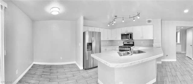 kitchen featuring light hardwood / wood-style flooring, kitchen peninsula, stainless steel appliances, sink, and white cabinets