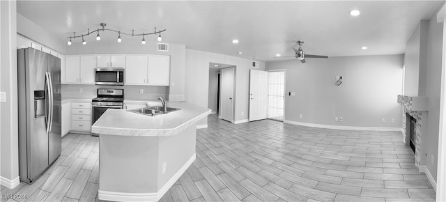 kitchen featuring kitchen peninsula, white cabinetry, ceiling fan, stainless steel appliances, and light hardwood / wood-style floors