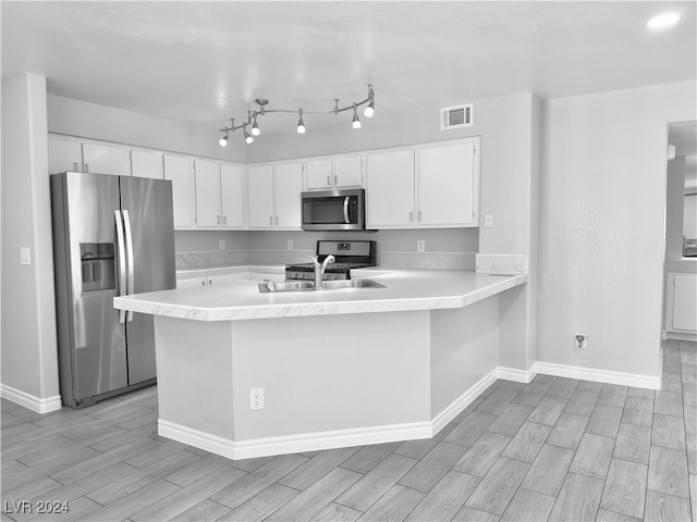 kitchen featuring sink, kitchen peninsula, white cabinetry, light hardwood / wood-style floors, and stainless steel appliances