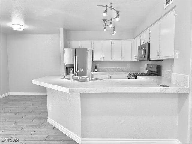 kitchen featuring kitchen peninsula, white cabinets, appliances with stainless steel finishes, light hardwood / wood-style floors, and sink