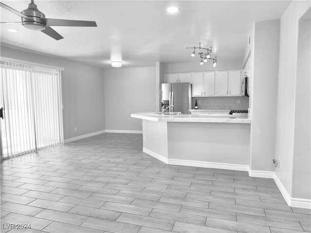 kitchen with light hardwood / wood-style floors, appliances with stainless steel finishes, kitchen peninsula, and white cabinets