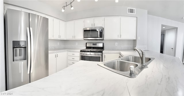 kitchen featuring white cabinetry, light stone counters, appliances with stainless steel finishes, and sink