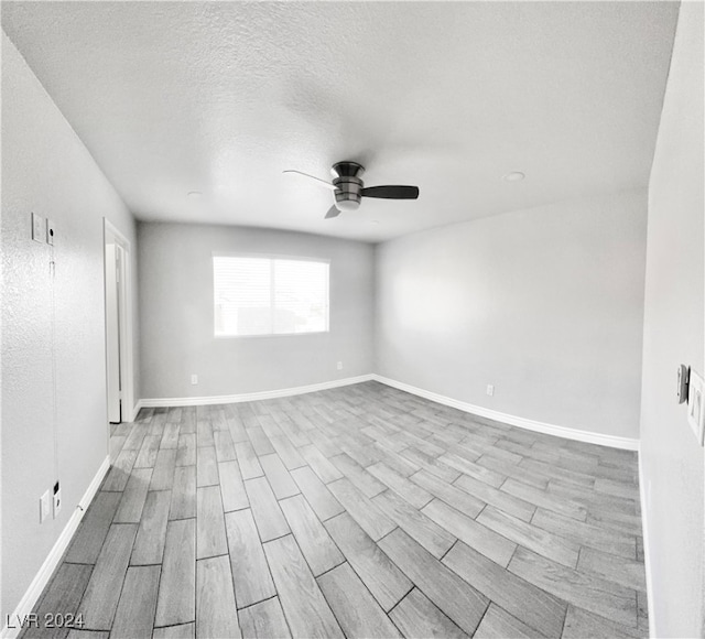 empty room featuring light hardwood / wood-style floors, a textured ceiling, and ceiling fan