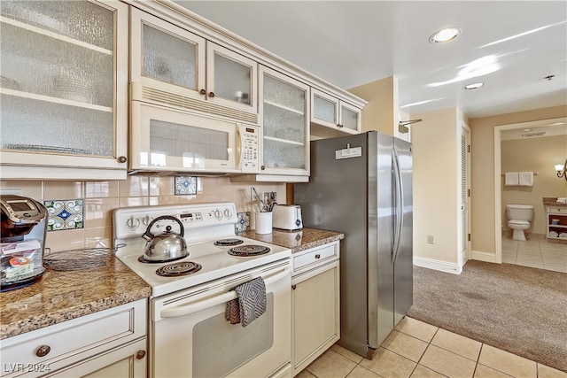 kitchen with cream cabinets, white appliances, light stone counters, decorative backsplash, and light tile patterned floors