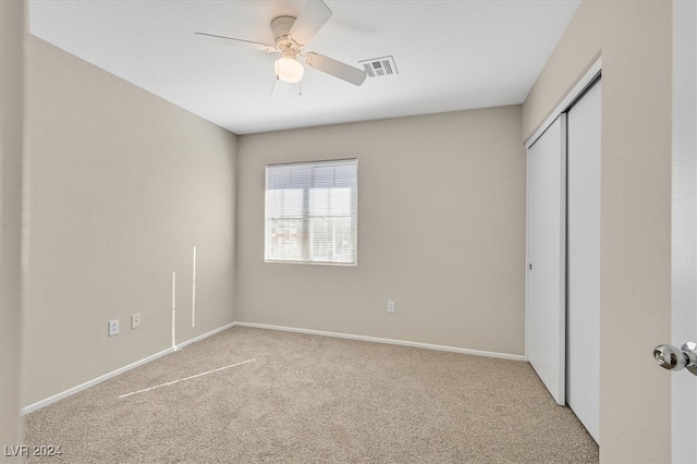 unfurnished bedroom featuring a closet, light colored carpet, and ceiling fan