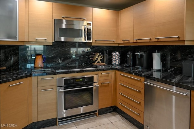 kitchen with backsplash, dark stone countertops, light tile patterned floors, and appliances with stainless steel finishes