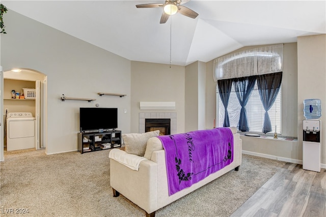 living room with a tiled fireplace, lofted ceiling, hardwood / wood-style flooring, ceiling fan, and washer / clothes dryer