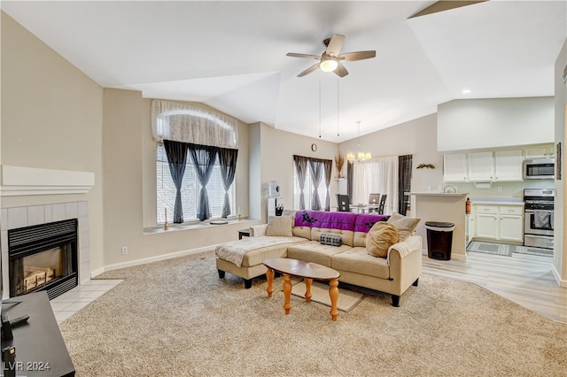 carpeted living room with a fireplace, vaulted ceiling, and ceiling fan with notable chandelier