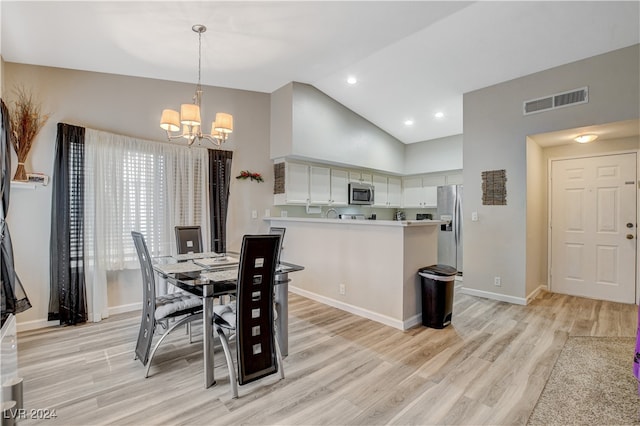 dining space with high vaulted ceiling, a chandelier, and light hardwood / wood-style flooring