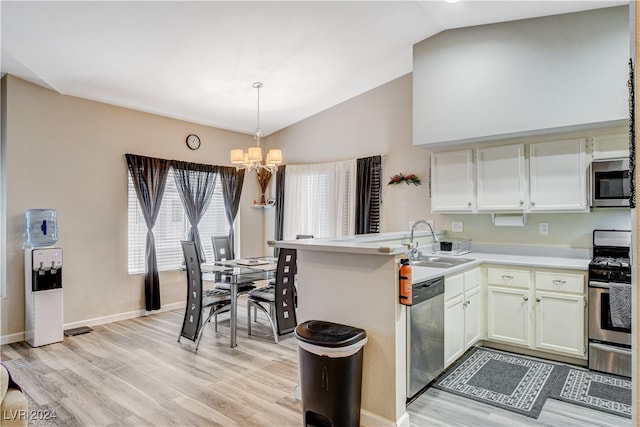 kitchen featuring light wood-type flooring, appliances with stainless steel finishes, kitchen peninsula, a chandelier, and lofted ceiling