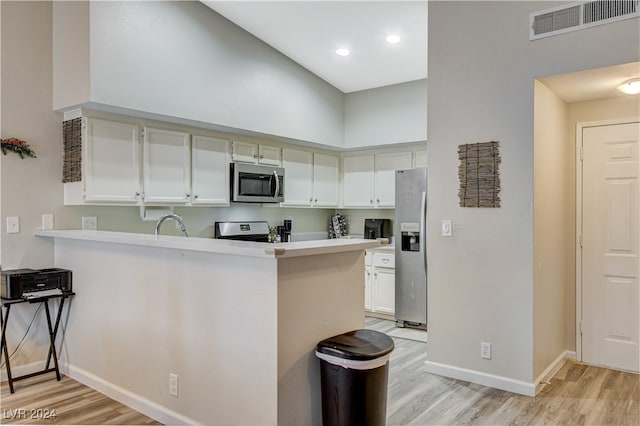 kitchen with kitchen peninsula, white cabinets, and appliances with stainless steel finishes