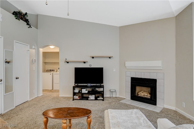 living room featuring separate washer and dryer, a tile fireplace, and light colored carpet