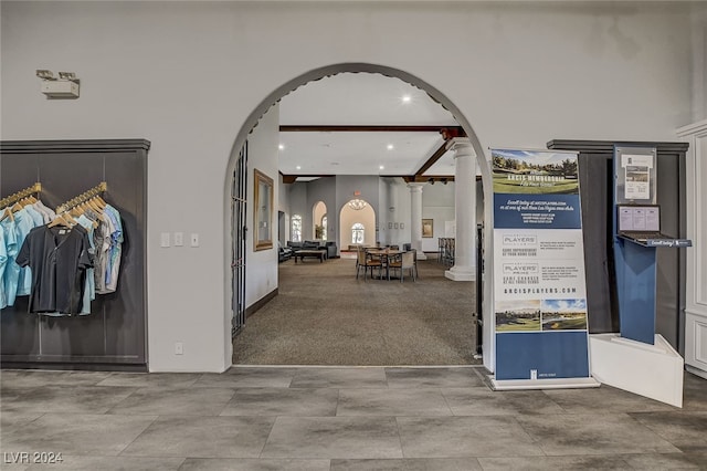 corridor with beamed ceiling, carpet, and decorative columns