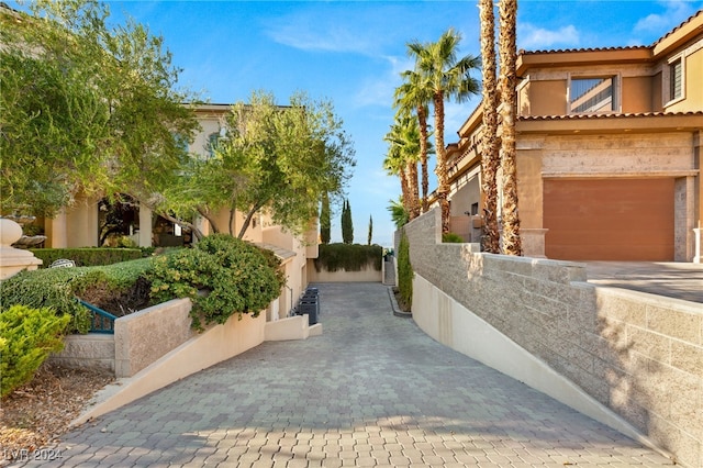 view of side of home with a tile roof, an attached garage, fence, and stucco siding