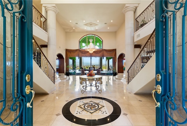 tiled entrance foyer with an inviting chandelier, ornate columns, a towering ceiling, recessed lighting, and stairs