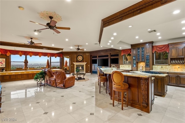 kitchen with tasteful backsplash, stainless steel gas cooktop, a large island, a kitchen breakfast bar, and light stone countertops