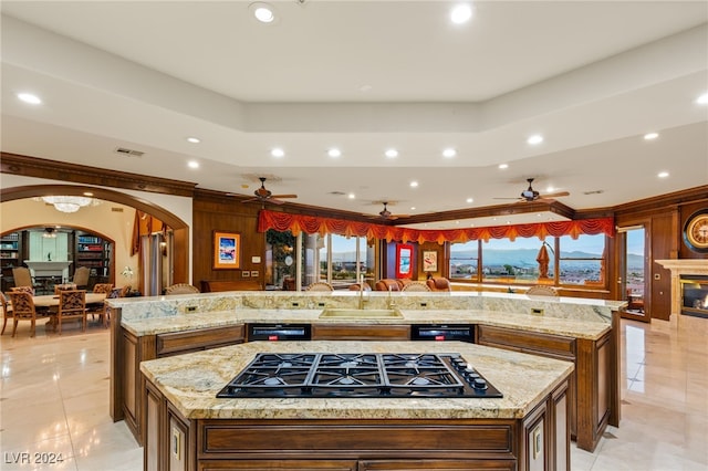 kitchen featuring arched walkways, a ceiling fan, black gas stovetop, and a spacious island