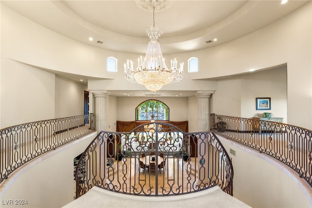 stairs featuring an inviting chandelier, a towering ceiling, and decorative columns