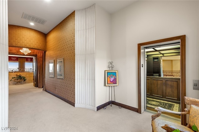 hallway with wallpapered walls, light colored carpet, baseboards, and visible vents