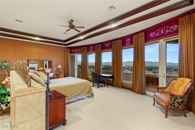 bedroom with ceiling fan, a mountain view, a tray ceiling, carpet floors, and crown molding