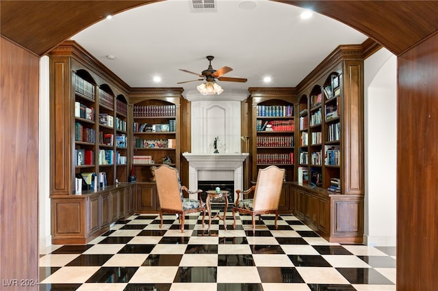 sitting room featuring built in features, tile patterned floors, a ceiling fan, and arched walkways