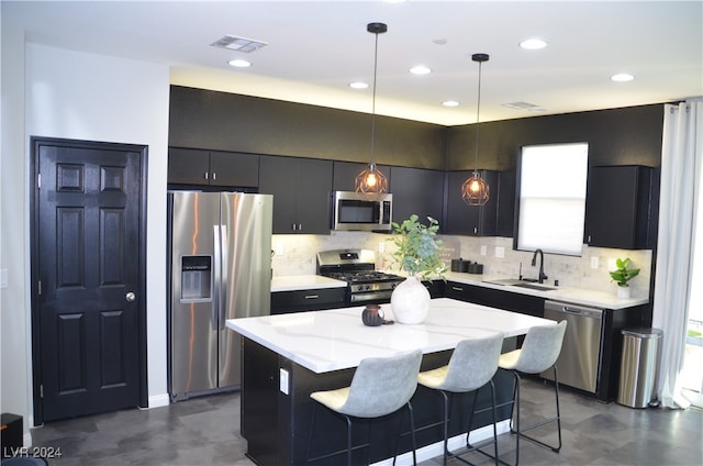 kitchen featuring backsplash, appliances with stainless steel finishes, a kitchen island, a kitchen bar, and pendant lighting