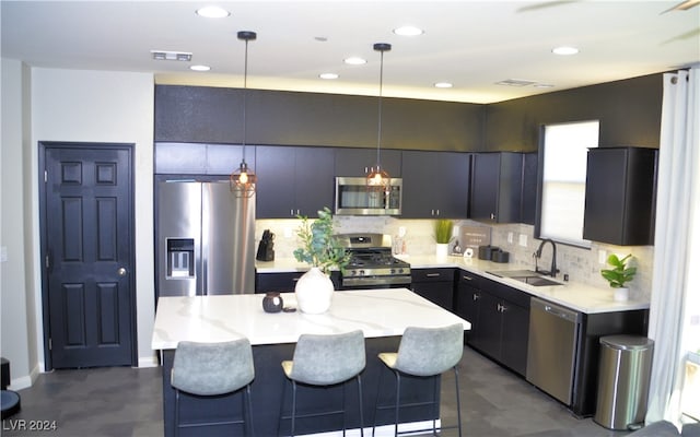 kitchen featuring decorative backsplash, a kitchen island, hanging light fixtures, stainless steel appliances, and sink