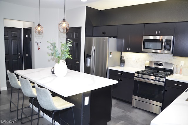 kitchen with a kitchen island, a kitchen bar, decorative light fixtures, appliances with stainless steel finishes, and tasteful backsplash