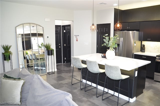 kitchen with a kitchen bar, a center island, stainless steel appliances, pendant lighting, and decorative backsplash