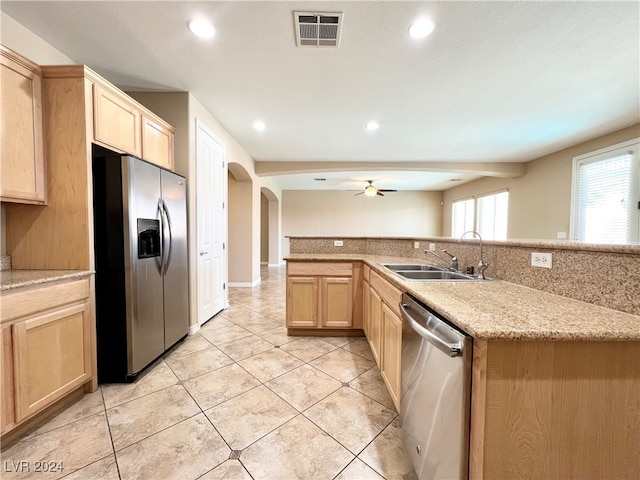 kitchen with ceiling fan, light brown cabinetry, sink, light stone countertops, and appliances with stainless steel finishes