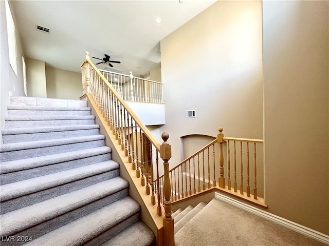 staircase with ceiling fan and carpet flooring