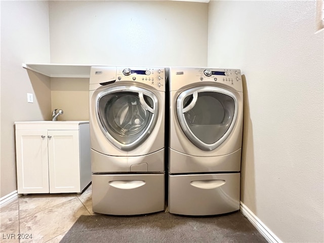 washroom featuring washing machine and dryer, cabinets, and light tile patterned floors