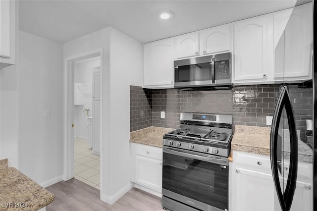 kitchen featuring light stone countertops, light wood-type flooring, white cabinetry, and appliances with stainless steel finishes