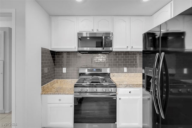 kitchen with light stone countertops, backsplash, stainless steel appliances, light tile patterned floors, and white cabinets