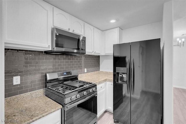 kitchen with tasteful backsplash, light stone counters, white cabinets, and appliances with stainless steel finishes