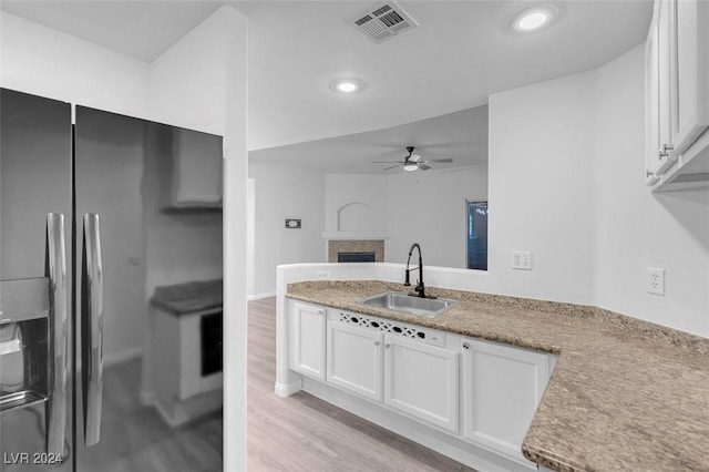 kitchen featuring stainless steel refrigerator with ice dispenser, light wood-type flooring, ceiling fan, sink, and white cabinetry