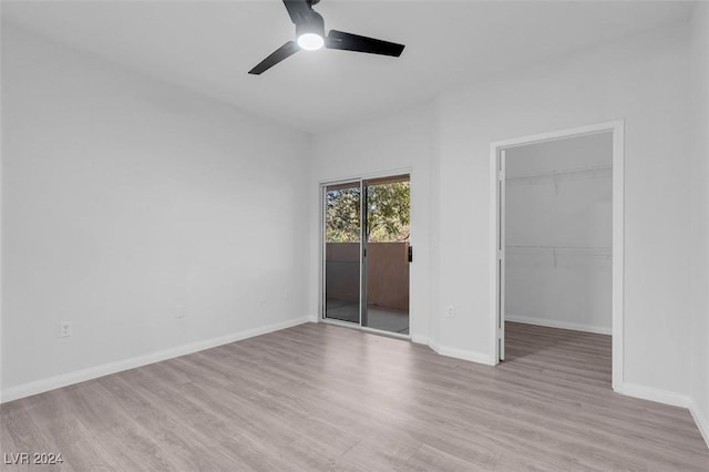 unfurnished bedroom with a walk in closet, ceiling fan, and light wood-type flooring