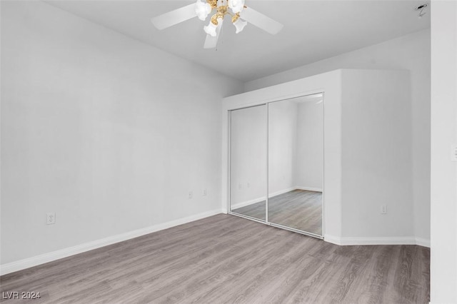 unfurnished bedroom with ceiling fan, light wood-type flooring, and a closet