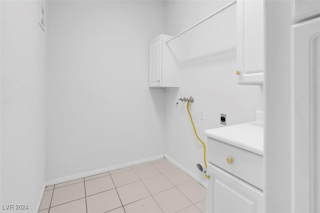 clothes washing area with hookup for an electric dryer, hookup for a washing machine, cabinets, and light tile patterned flooring