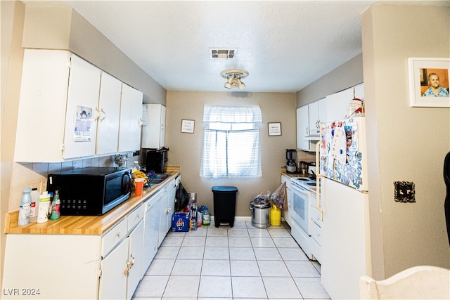 kitchen featuring light tile patterned flooring, a textured ceiling, white appliances, and white cabinetry