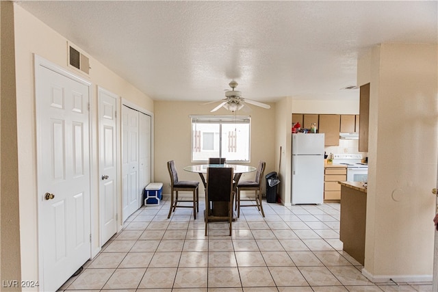 tiled dining area with ceiling fan and a textured ceiling