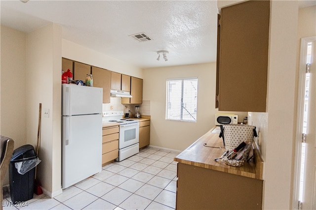 kitchen with light tile patterned flooring, a textured ceiling, and white appliances