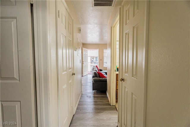 hall featuring a textured ceiling and light hardwood / wood-style floors