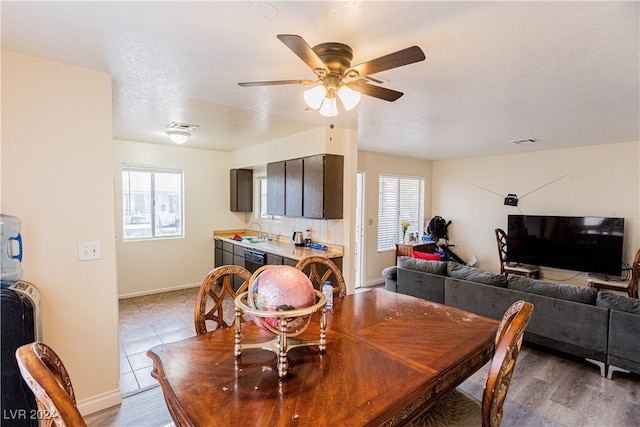 dining space featuring light tile patterned flooring, ceiling fan, sink, and a textured ceiling