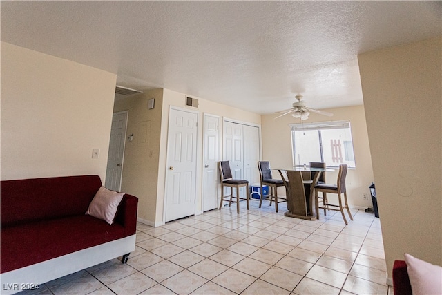 tiled living room with ceiling fan and a textured ceiling