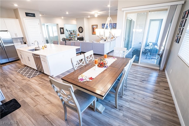 dining space featuring an inviting chandelier, light hardwood / wood-style floors, sink, and a wealth of natural light