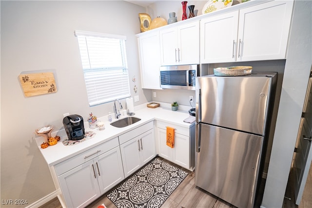 kitchen featuring white cabinets, stainless steel appliances, sink, and light hardwood / wood-style flooring