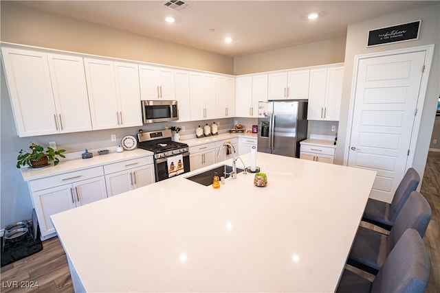 kitchen featuring an island with sink, dark wood-type flooring, sink, white cabinetry, and appliances with stainless steel finishes