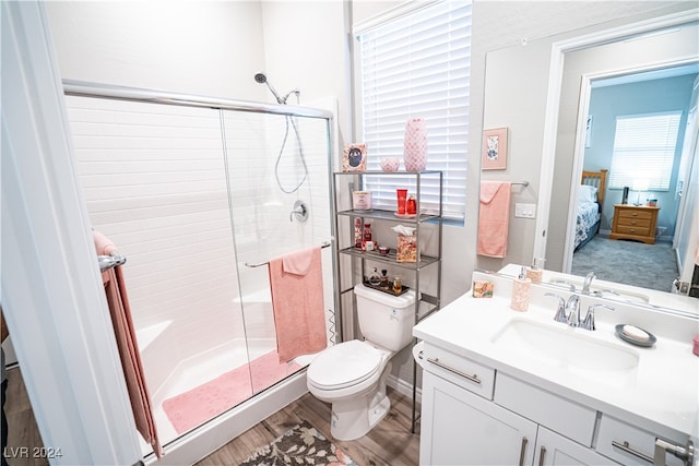 bathroom featuring wood-type flooring, vanity, toilet, and a shower with door