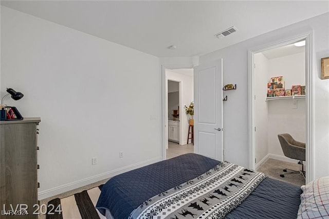 bedroom with a closet, light colored carpet, and a walk in closet